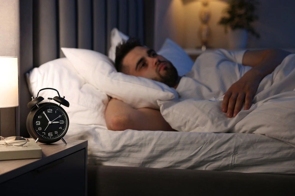 Frustrated man suffering from insomnia on bed
